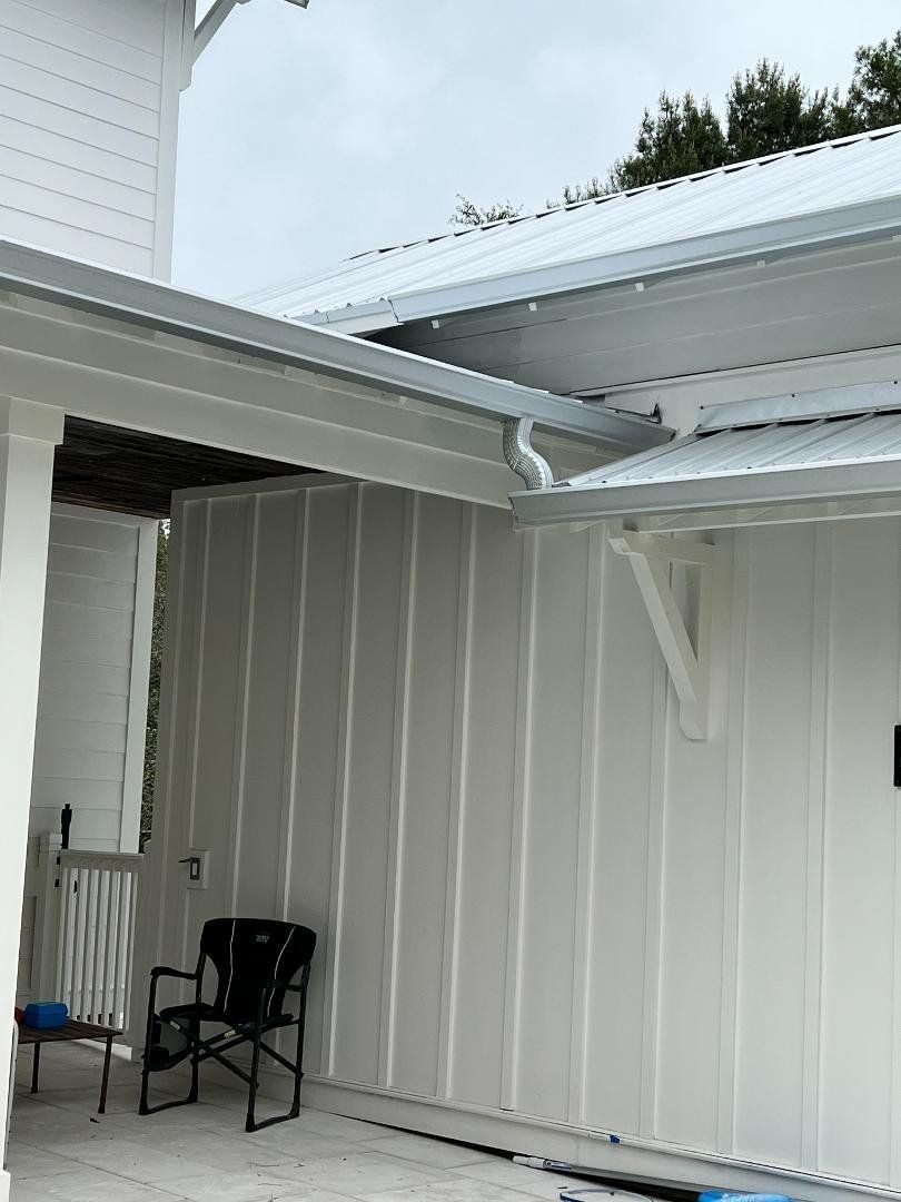 A white house with a black chair on the porch.