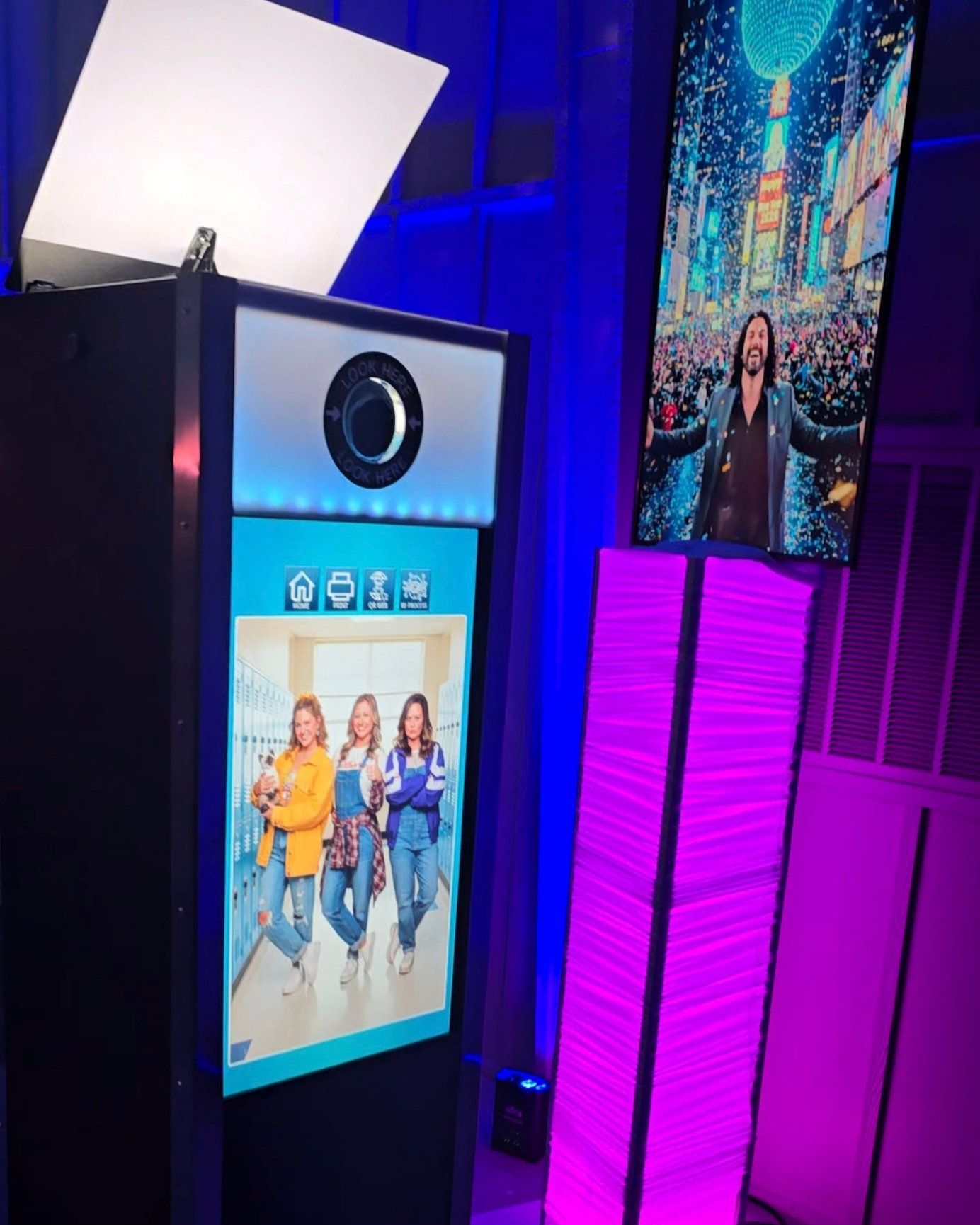 Interactive digital AI photo booth kiosk with colorful LED lighting at an event venue