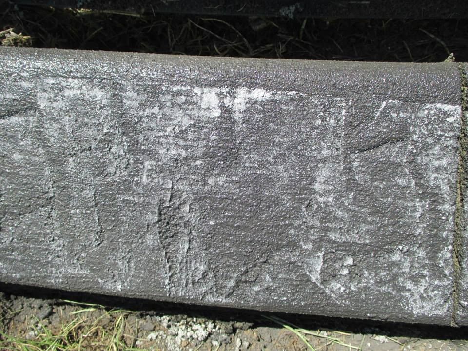 Dark, weathered curb with peeling paint and white discoloration, likely from salt or weathering.