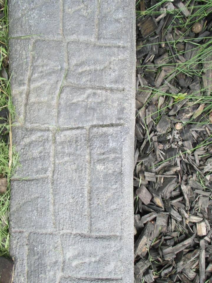 Gray brick border next to wood chip mulch and grass.