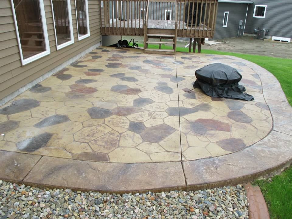 Stamped concrete patio with stone pattern, next to a deck and lawn.