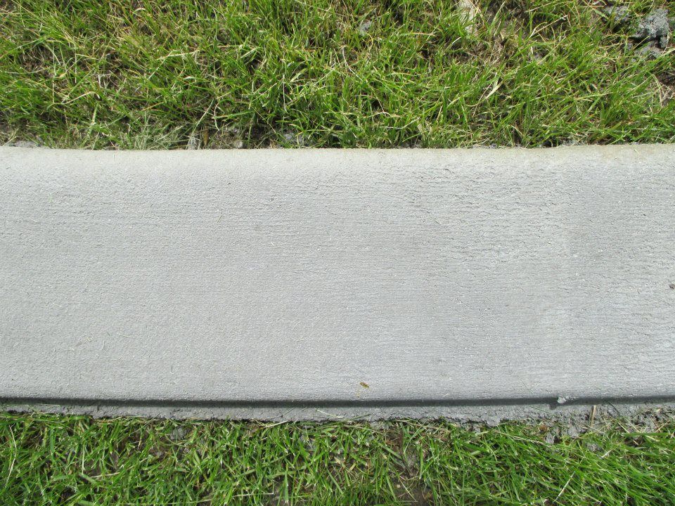 Gray concrete curb bordering green grass.