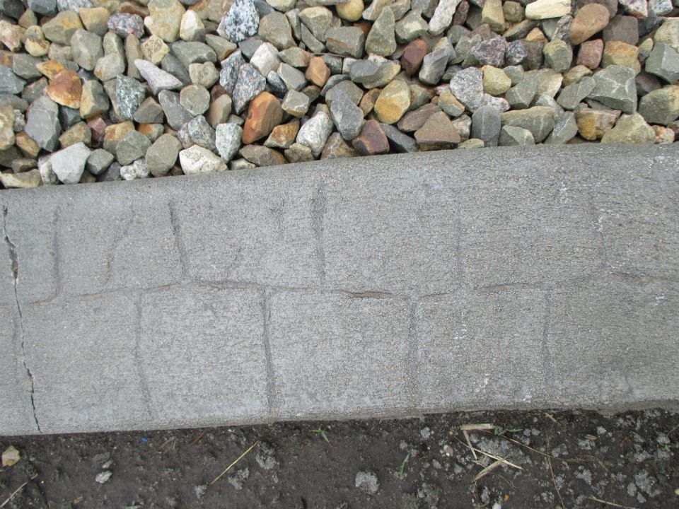 Gray stone border with cracks, rocks above, dirt below.