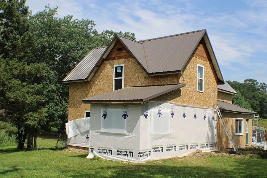 A two-story house under construction with brown metal roofing.
