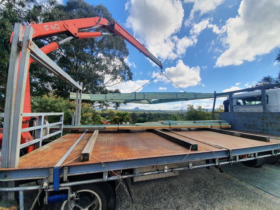 Unloading Timber Roof Trusses With Glass House Mountains In The Background — Roof Trusses in Caboolture, QLD