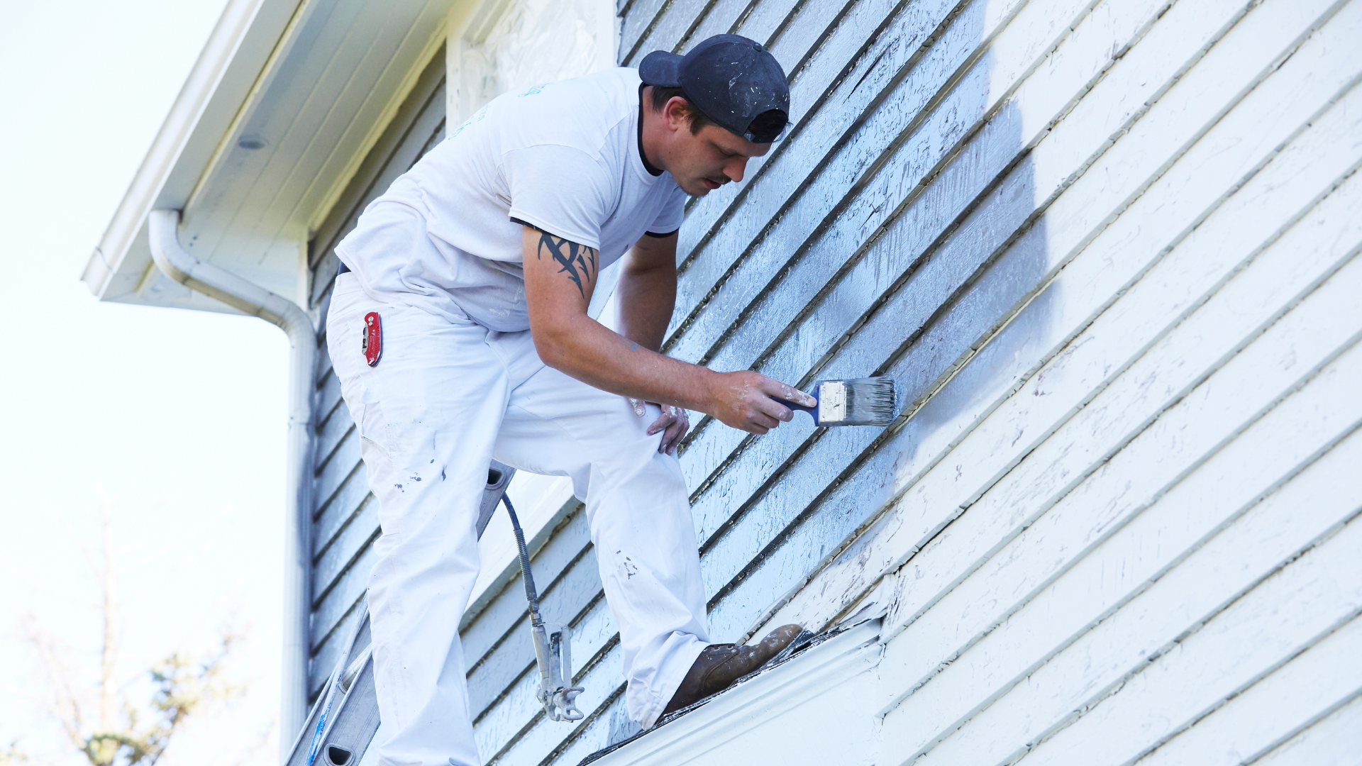A man is painting the side of a house with a brush.