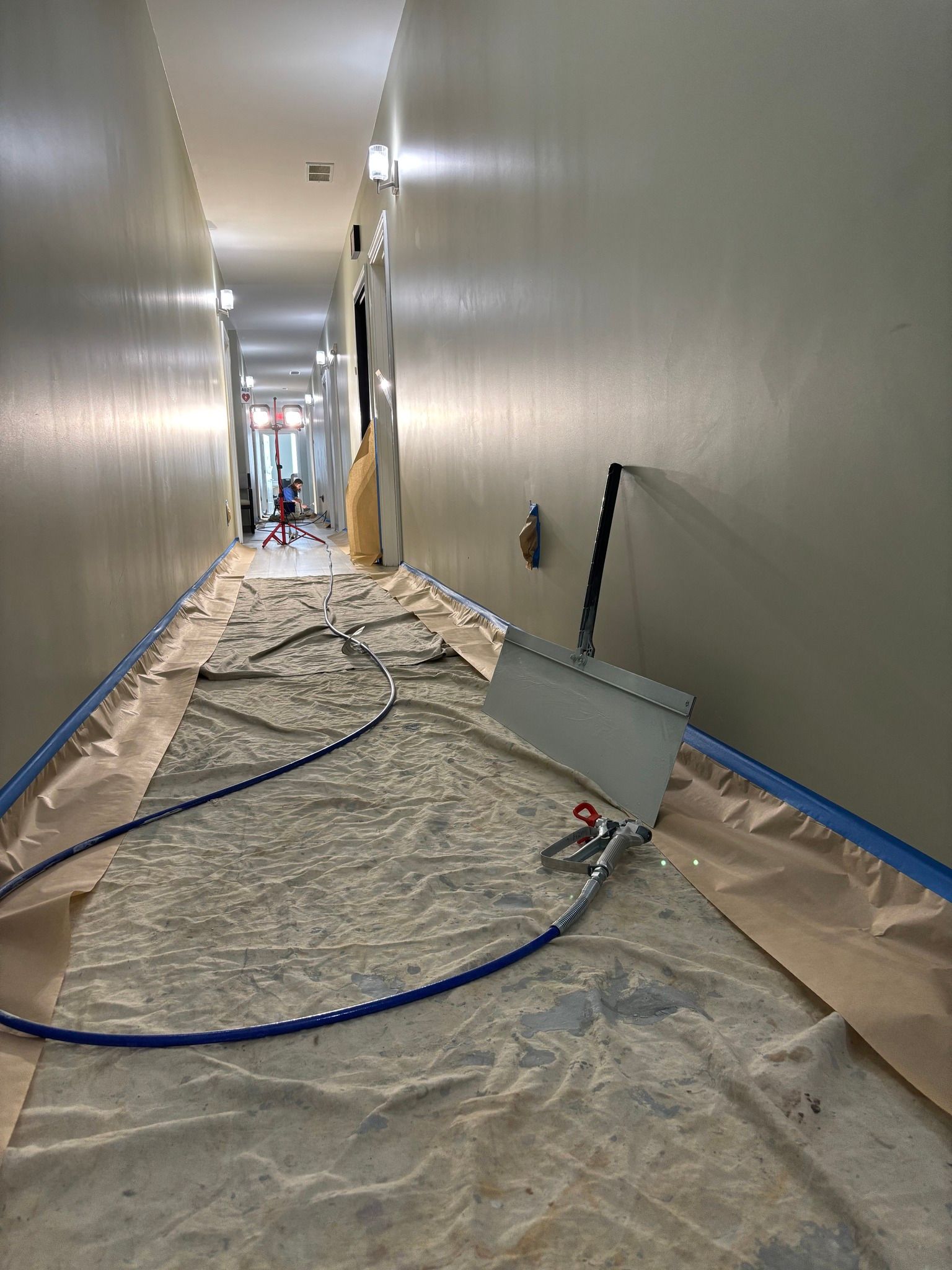 Hallway under renovation, covered with protective sheeting and equipment.