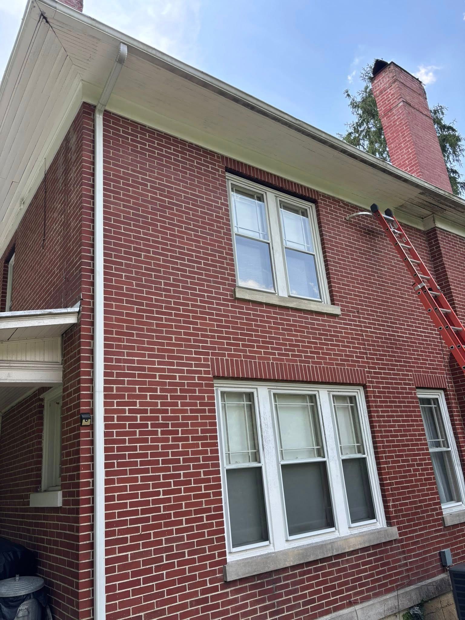 Red brick building with white trim and windows under a blue sky.