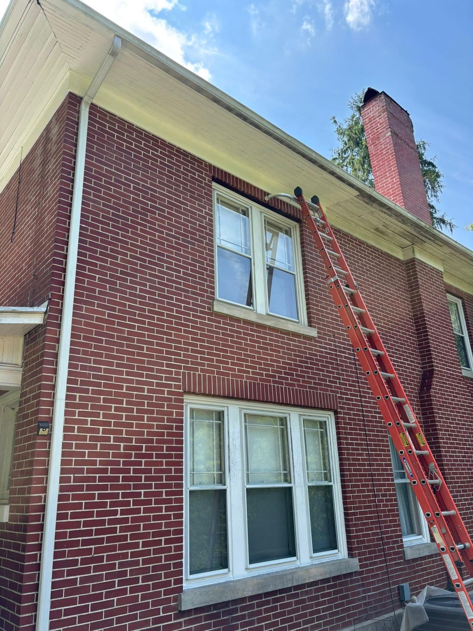 Red brick building with a red ladder propped up against the side. The sky is visible.