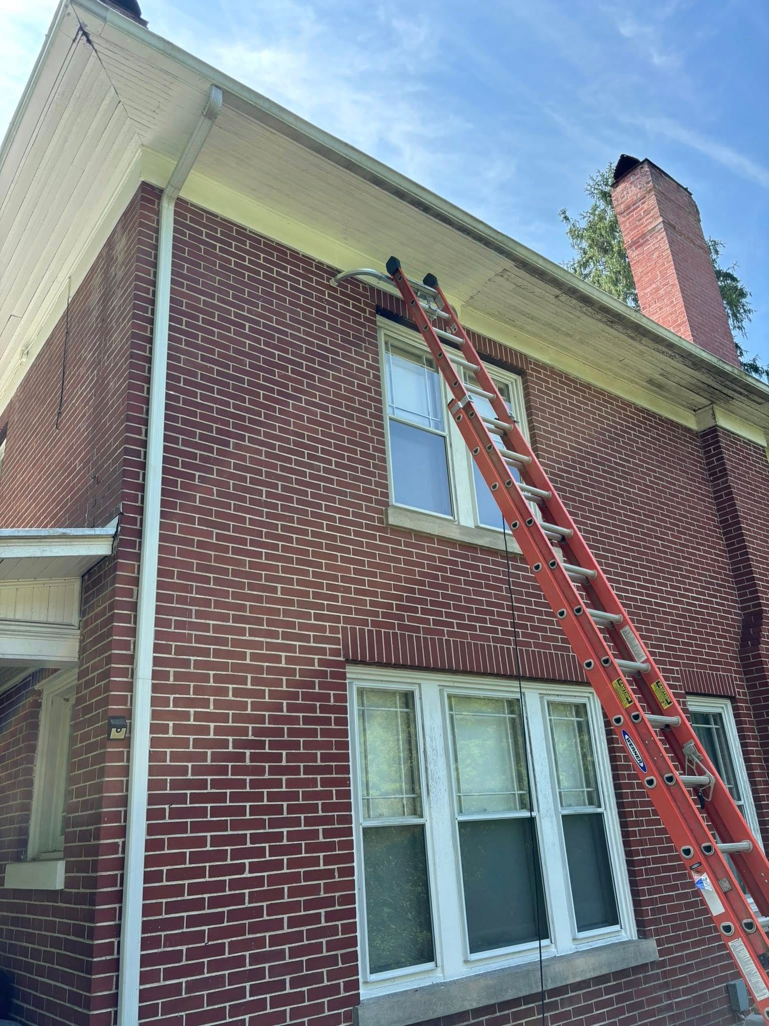 Red brick house with an orange ladder leaning against the side.