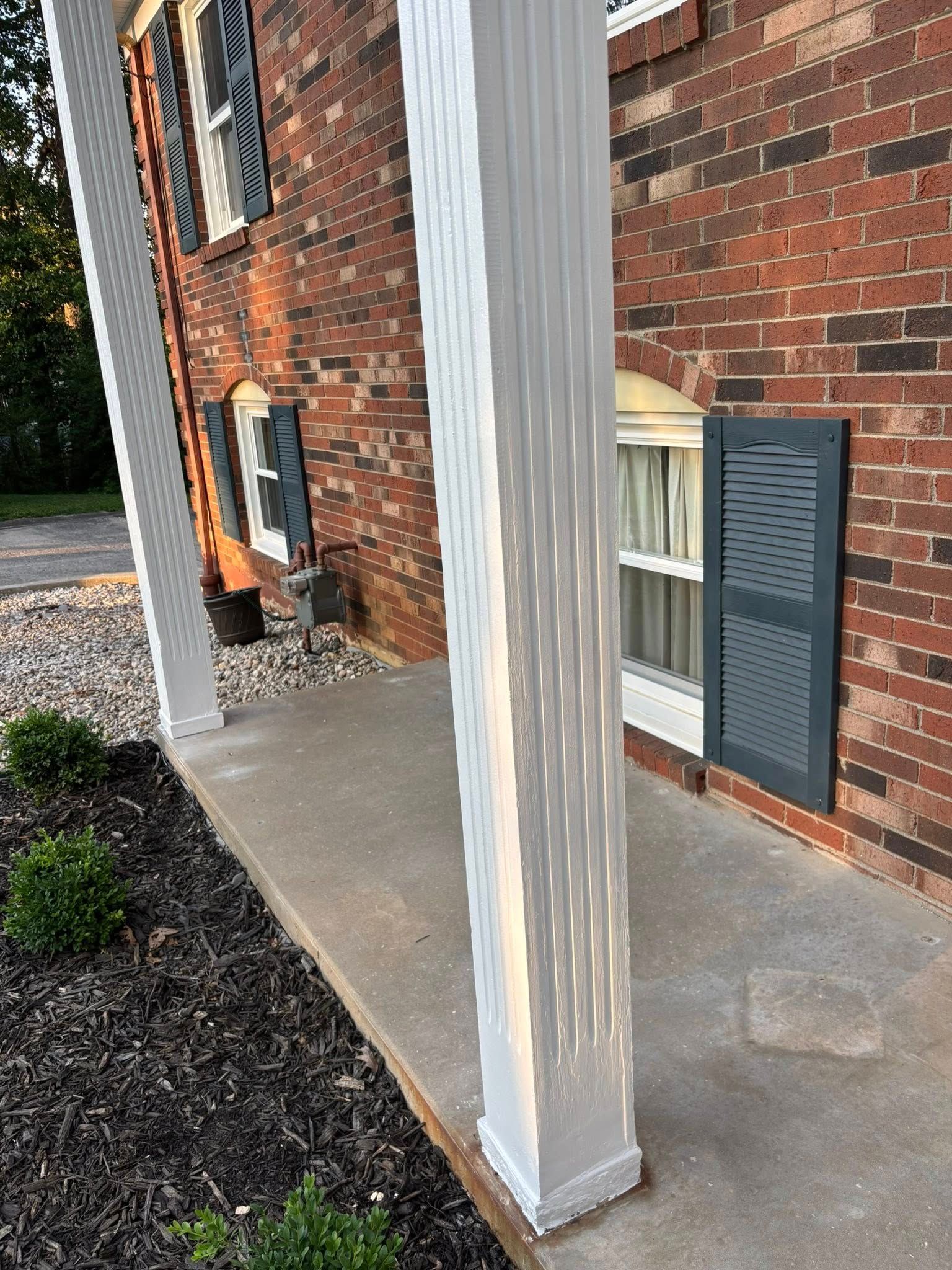 Brick building exterior with white pillars and gray shutters.