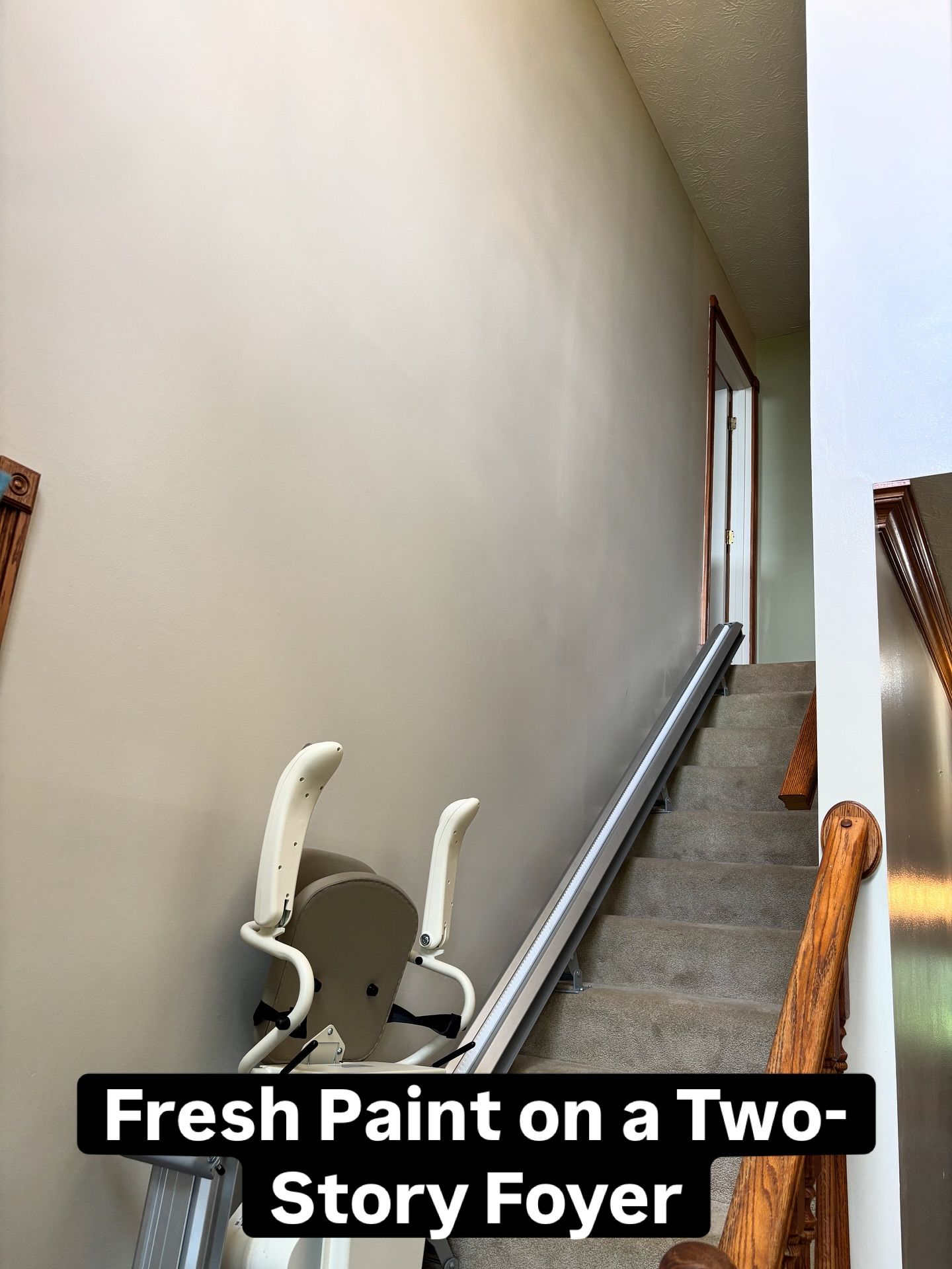 Staircase with a lift and freshly painted walls in a two-story foyer.