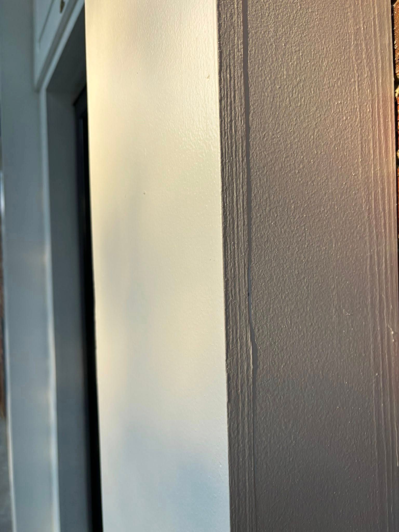 A stack of dark gray paper next to a smooth, light gray wall.