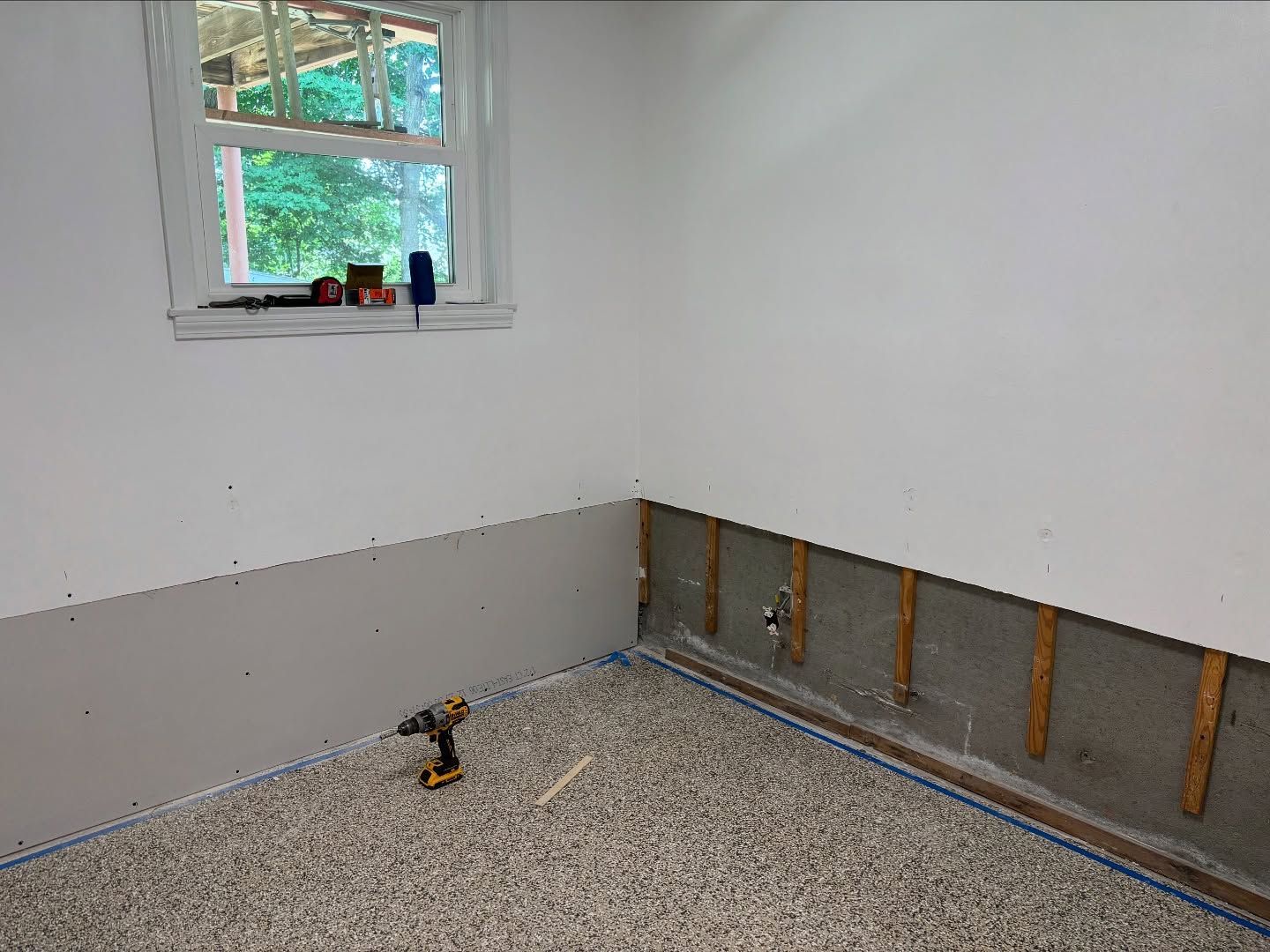 Interior room with drywall partially installed; a cordless drill sits on the floor.