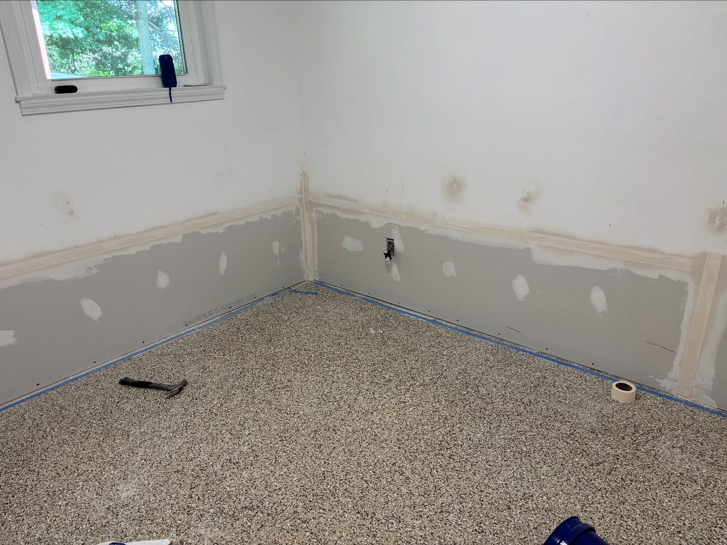 Room under renovation, drywall installed on lower walls, carpeted floor.