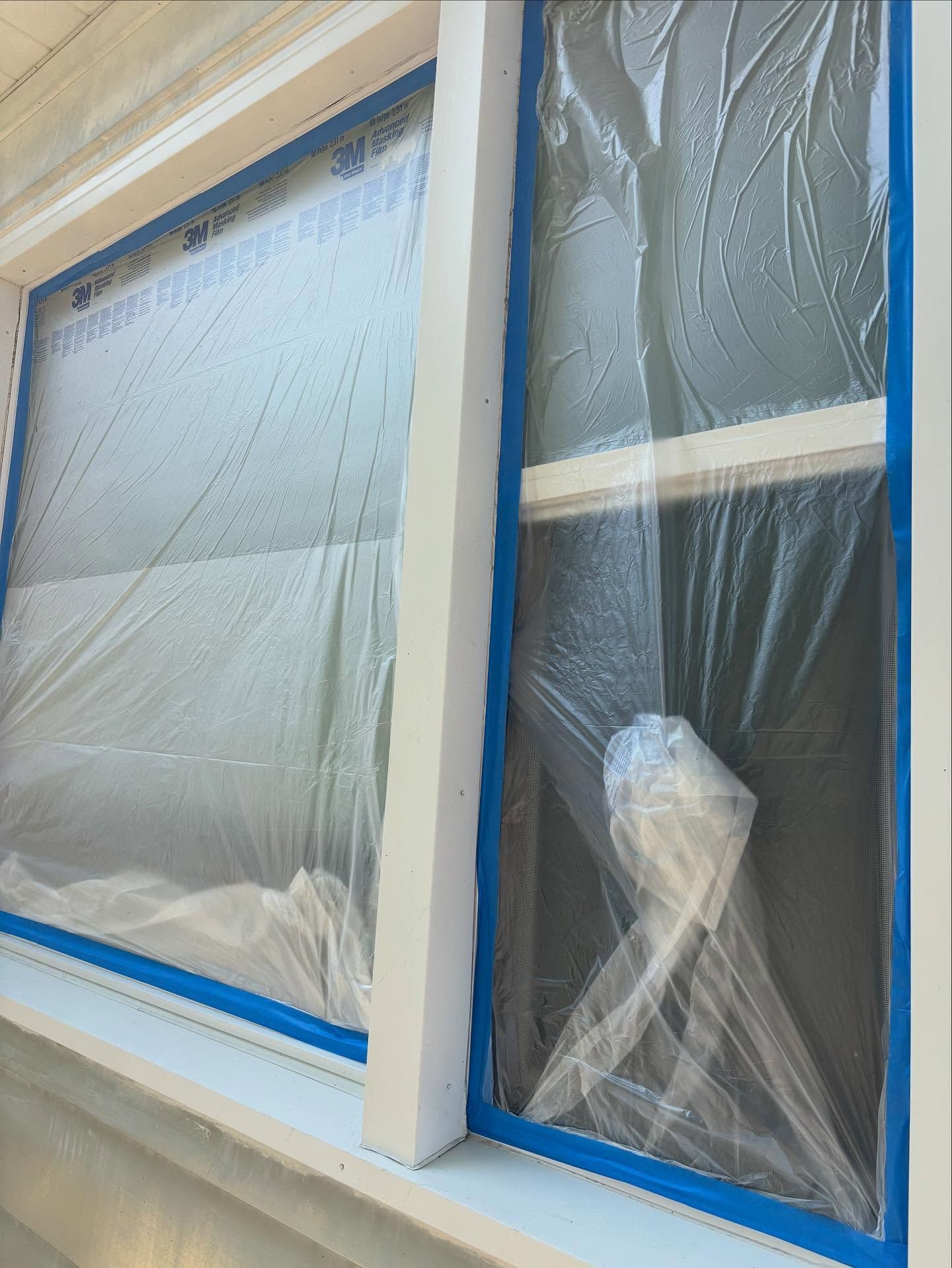 Windows prepped for painting with blue tape and plastic sheeting.