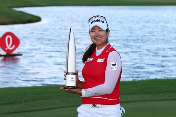 A woman is holding a trophy on a golf course.