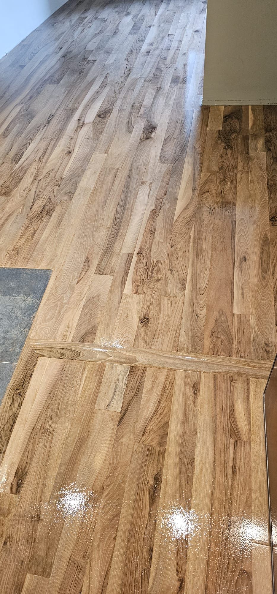 Pavimento in legno in una stanza. Sono visibili alcuni punti lucidi, probabilmente dovuti a una superficie lucida.