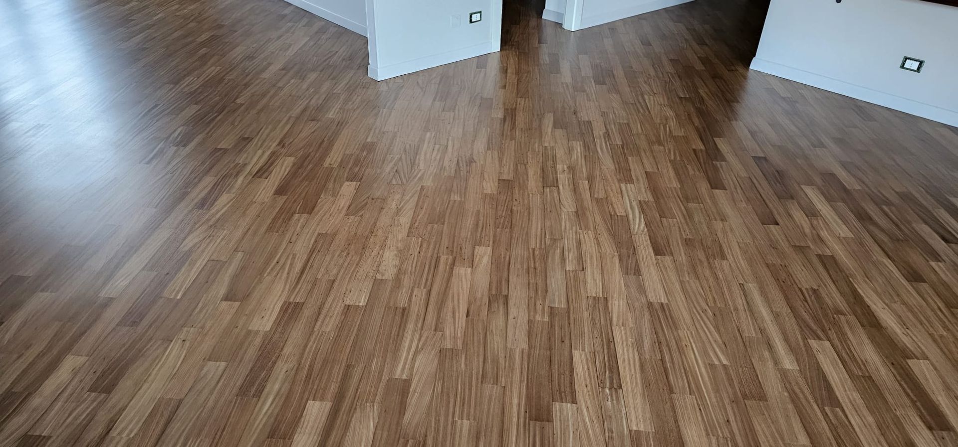 Pavimento in legno con finitura lucida. Sono visibili gli stipiti bianchi delle porte.