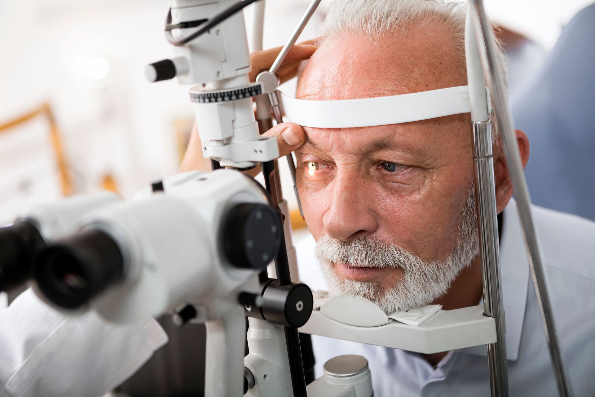 A woman is examining a man's eye with an eye apparatus