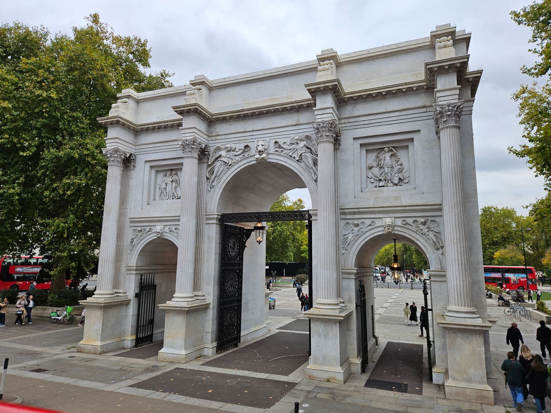 Marble Arch, London: white marble archway with carved details. People and red buses are in the background.