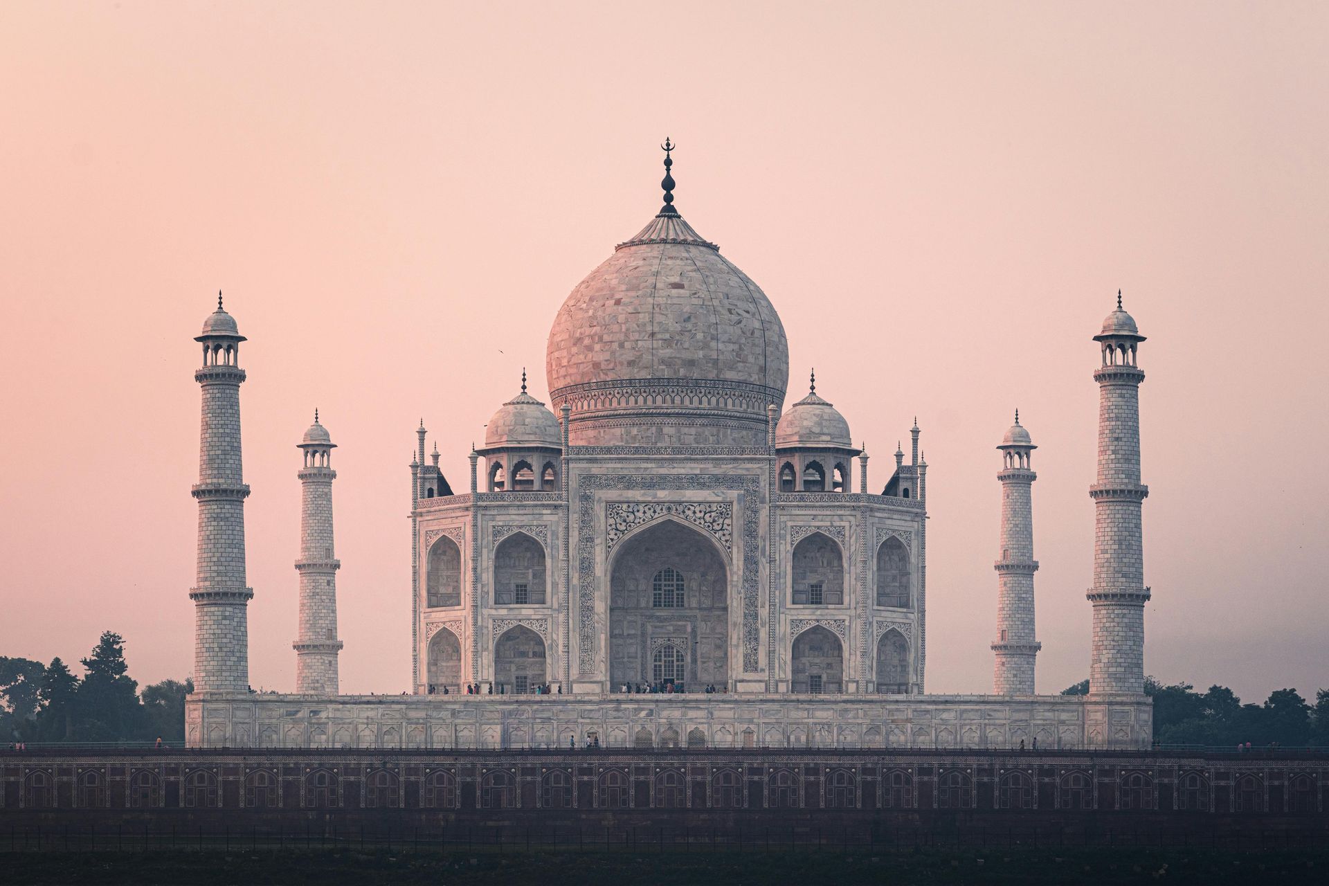 Taj Mahal, white marble mausoleum with dome and minarets against pink sky. Agra, India.
