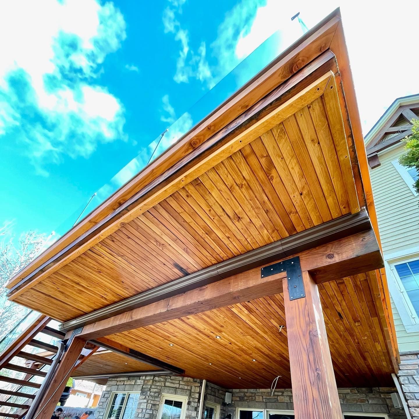 Un porche en bois avec des escaliers et un ciel bleu en arrière-plan.