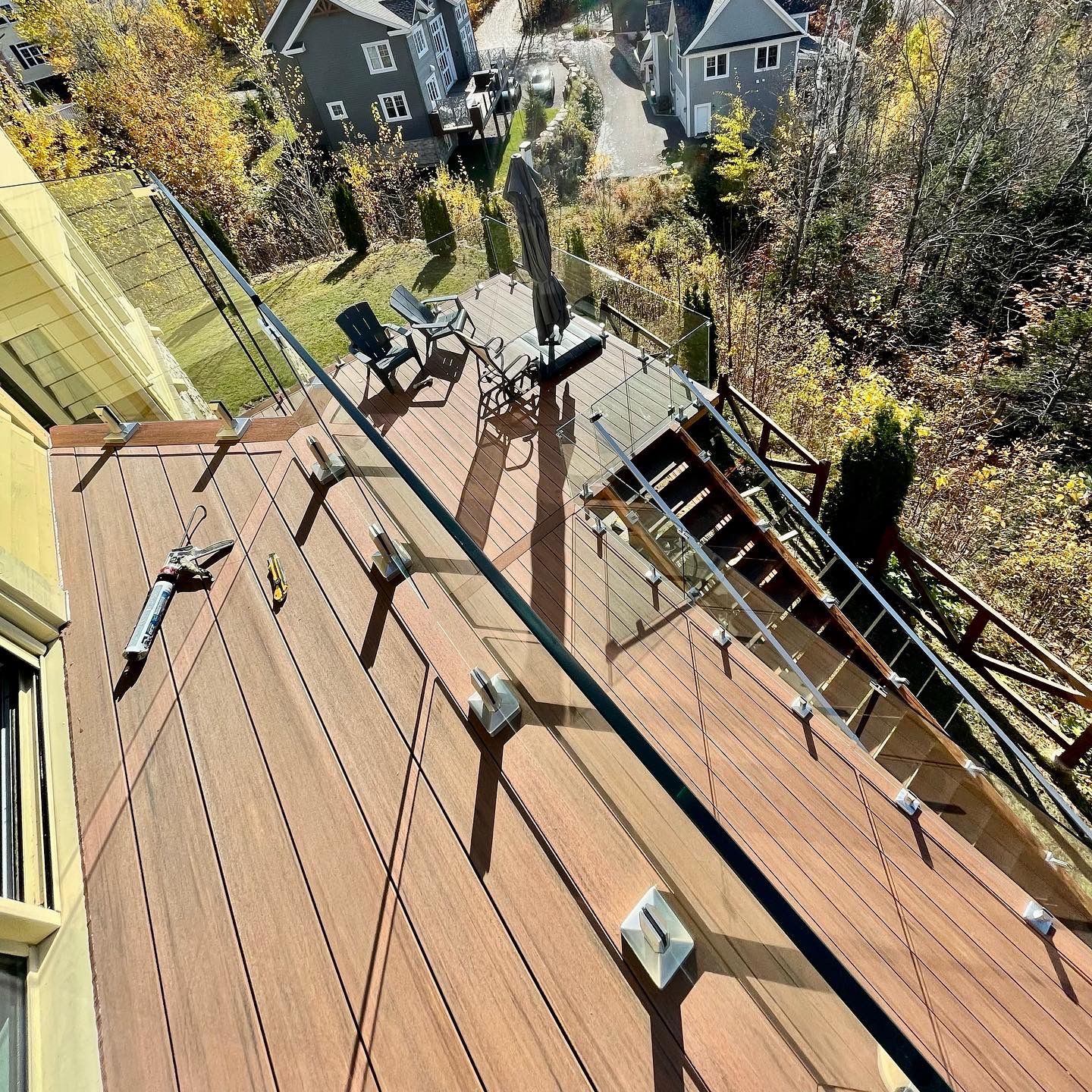 Une vue aérienne d'une terrasse en bois avec des escaliers et une balustrade en verre.