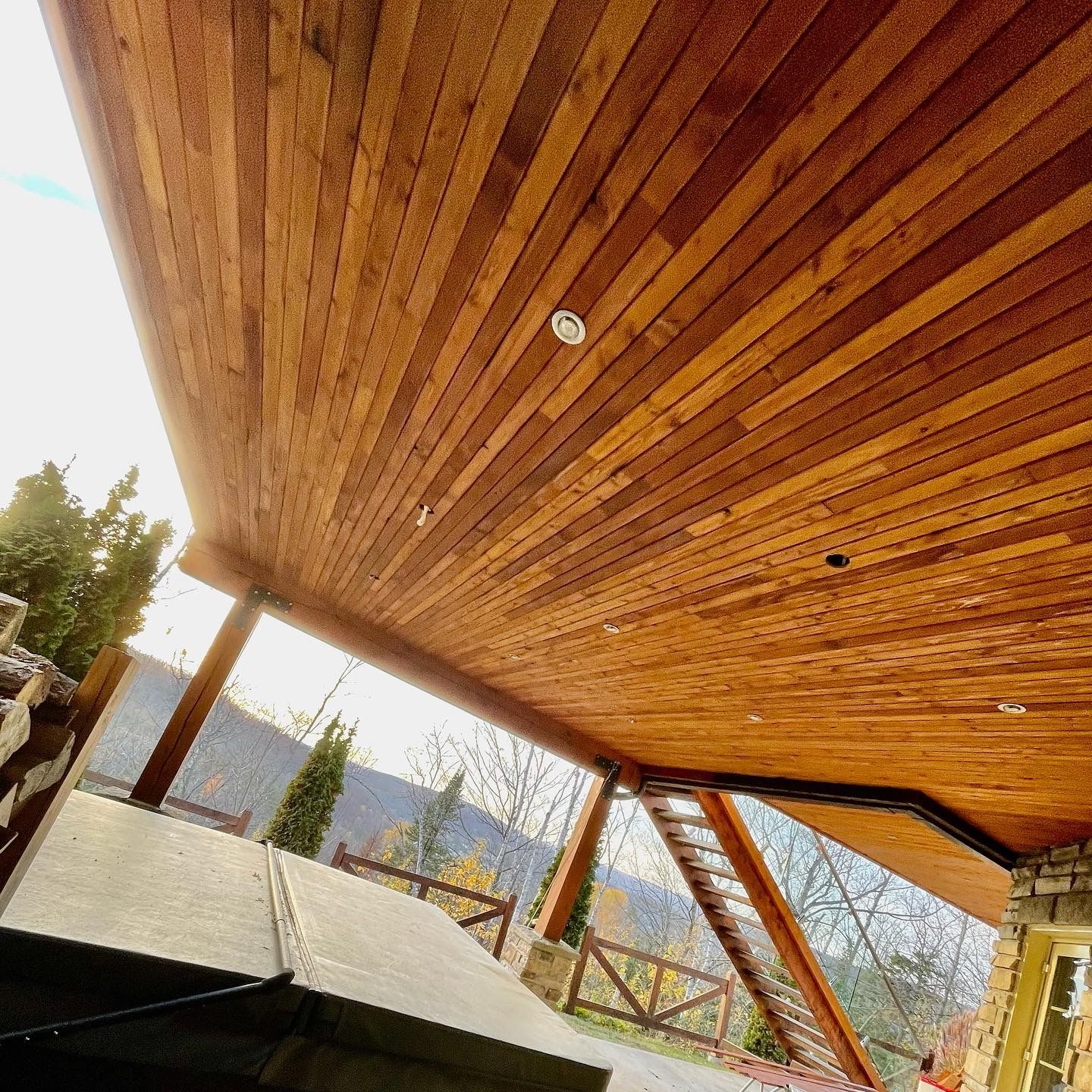 Le plafond d'une terrasse en bois avec des escaliers qui y mènent.