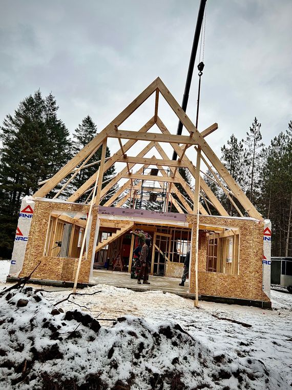 Une maison est en construction dans la neige avec une grue en arrière-plan.