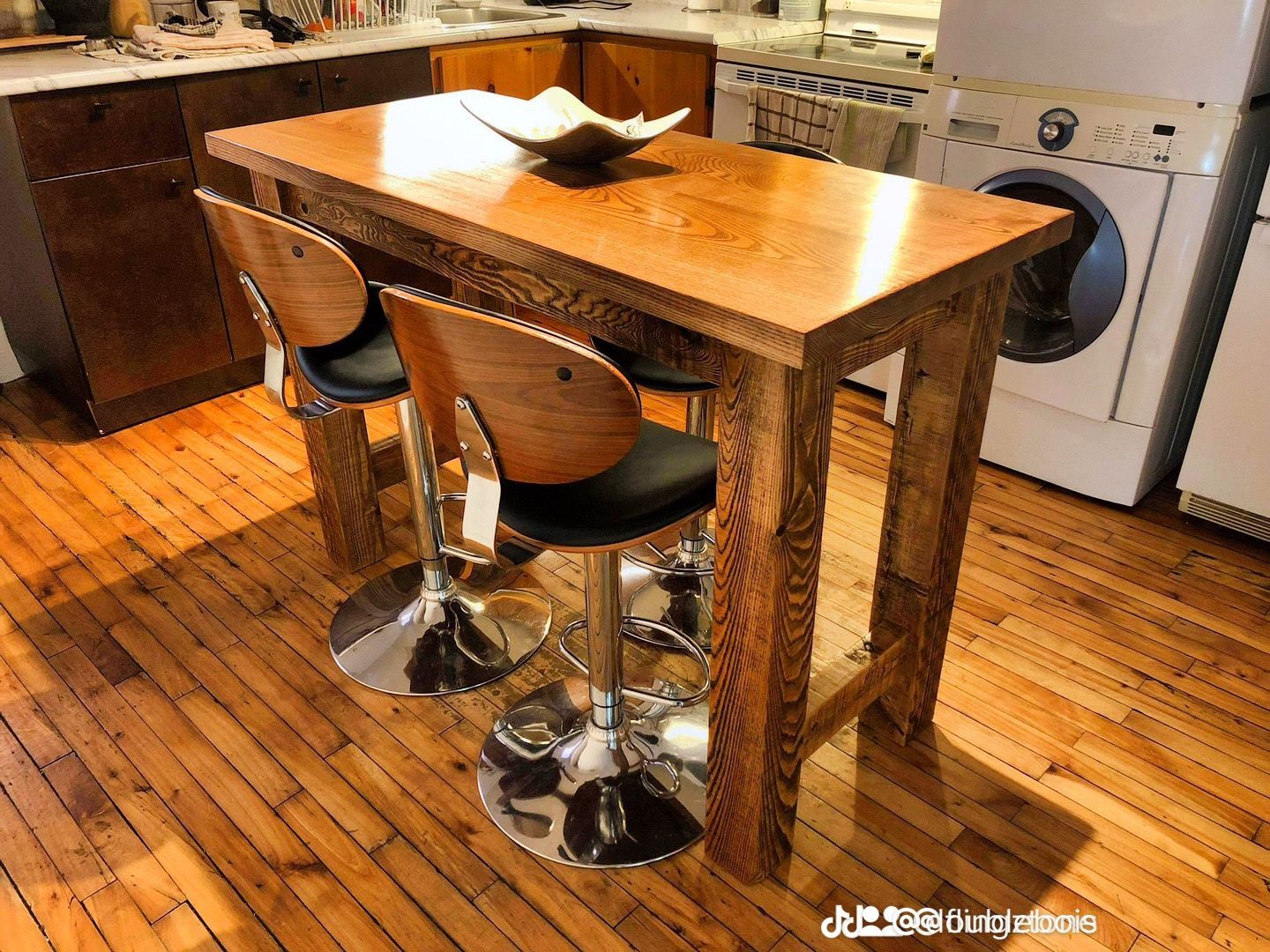 Une cuisine avec une table et des chaises en bois et une laveuse et une sécheuse