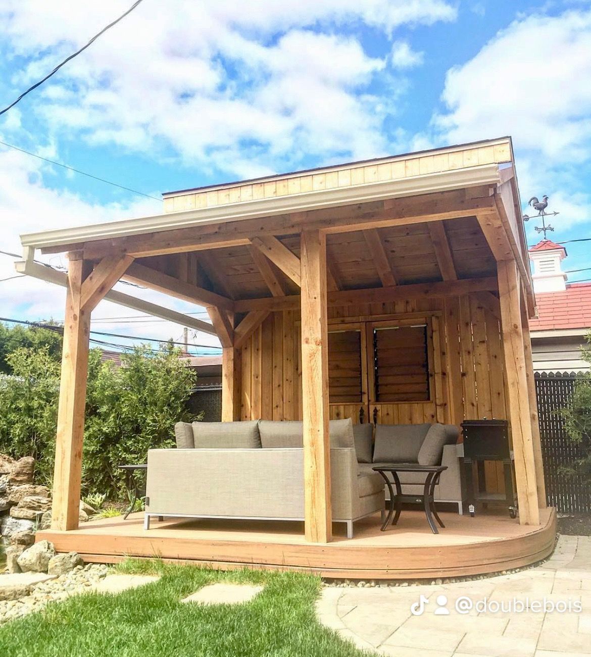 Un gazebo en bois avec un canapé et une table en dessous.