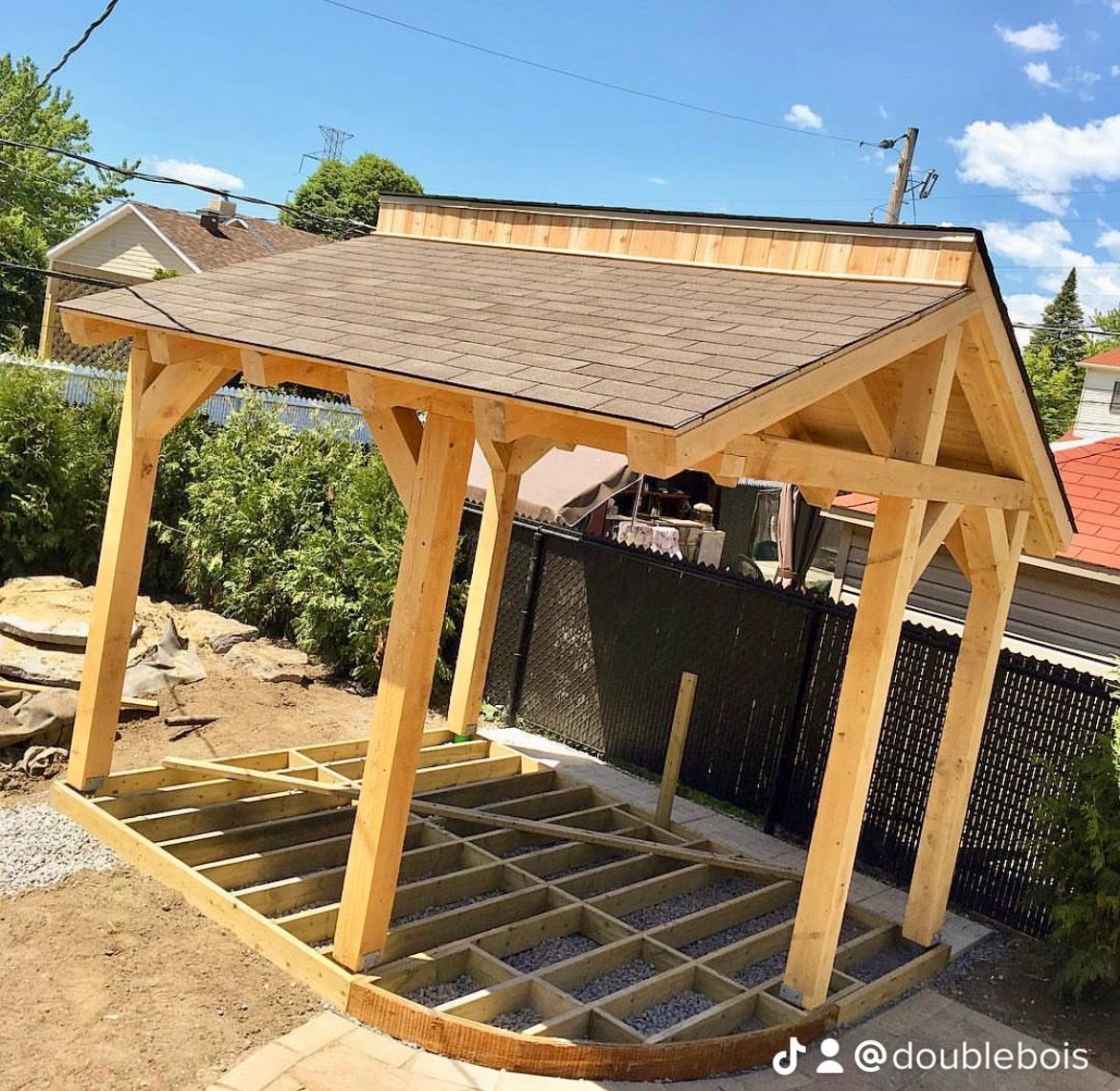 Une structure en bois avec un toit est en cours de construction dans une arrière-cour.