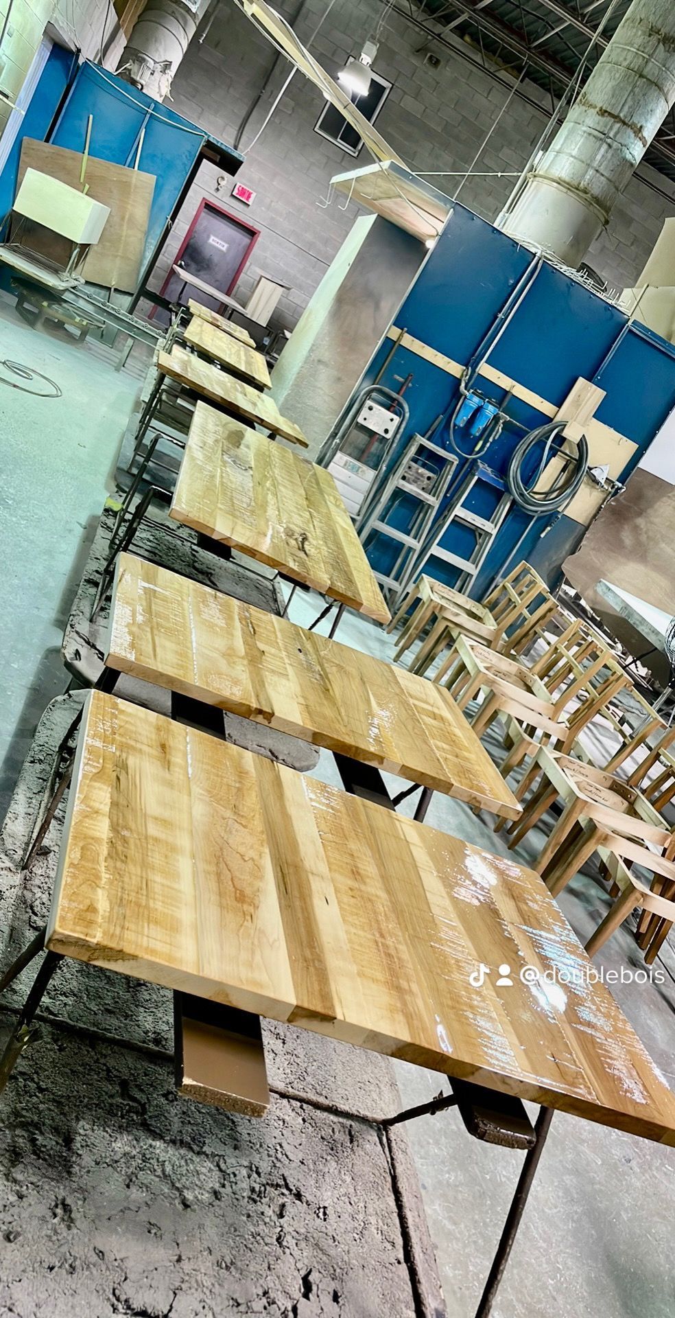 Une rangée de tables en bois est posée dans une pièce d'une usine.