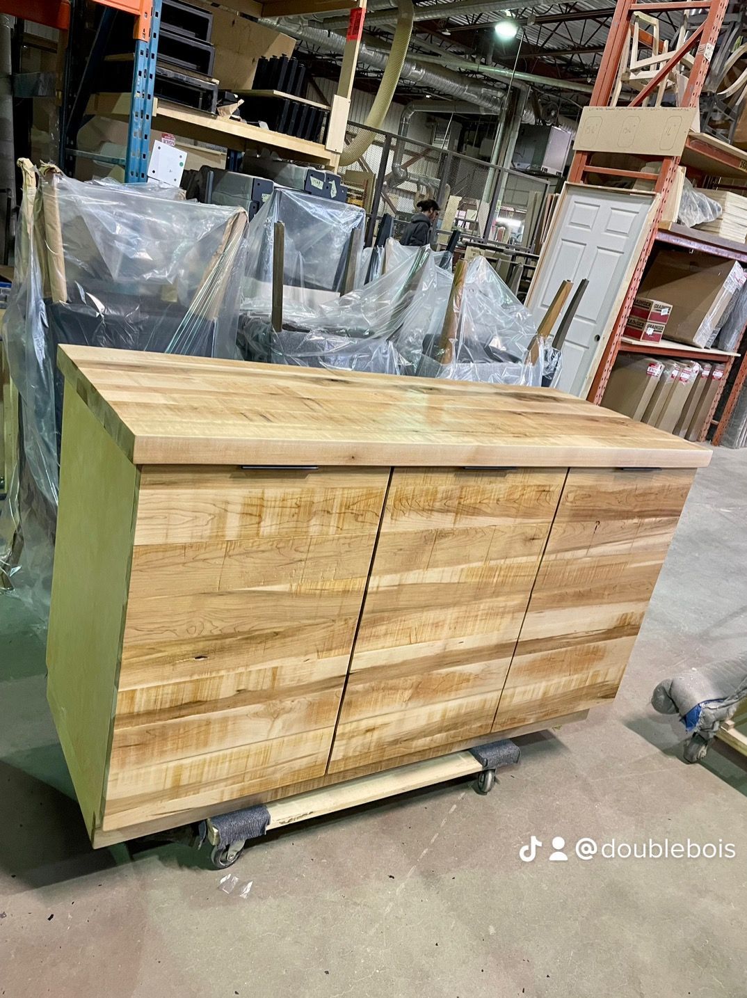 Une commode en bois est posée sur un chariot dans un entrepôt.