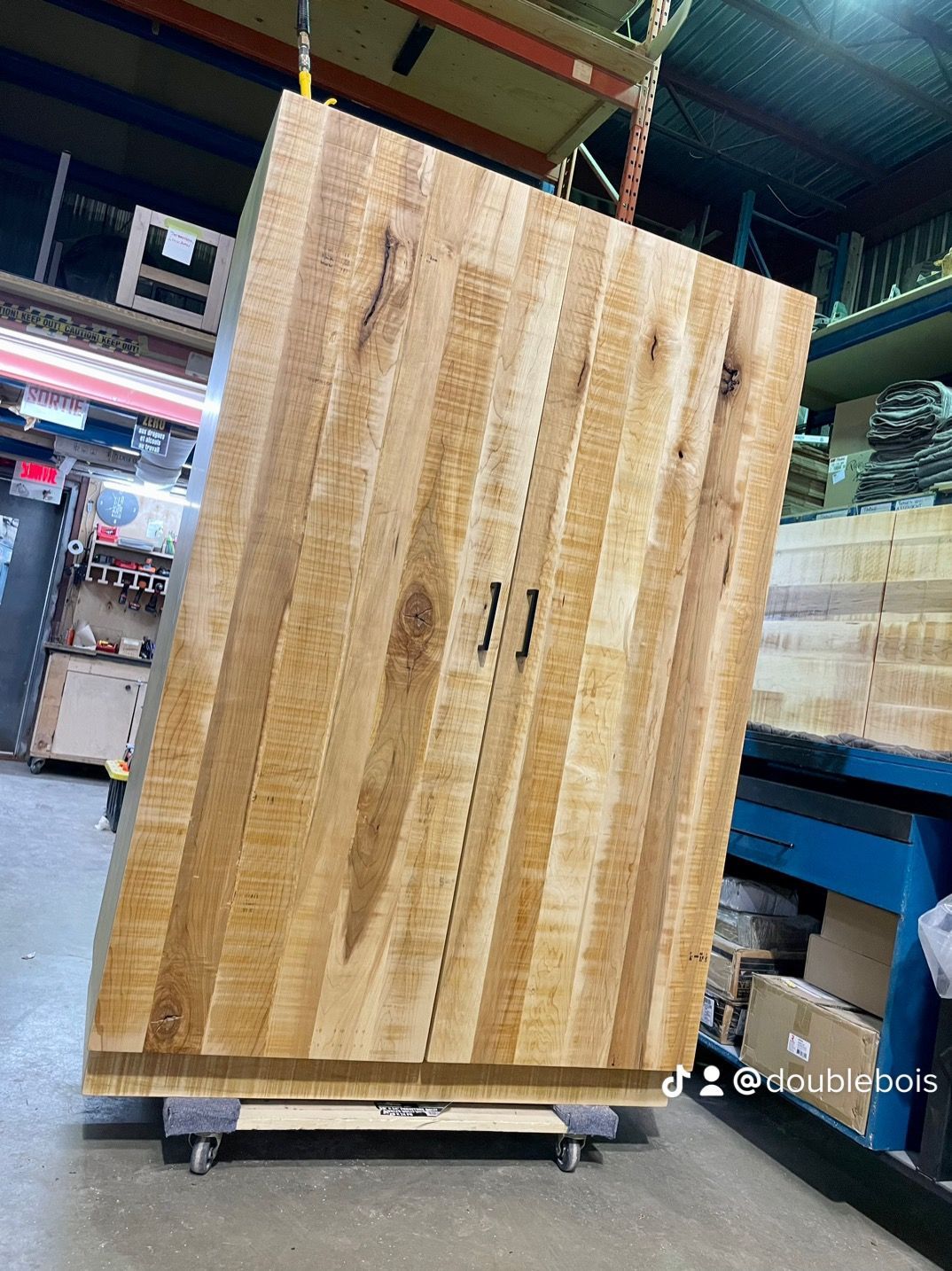 Une grande armoire en bois est posée sur un chariot dans un entrepôt.