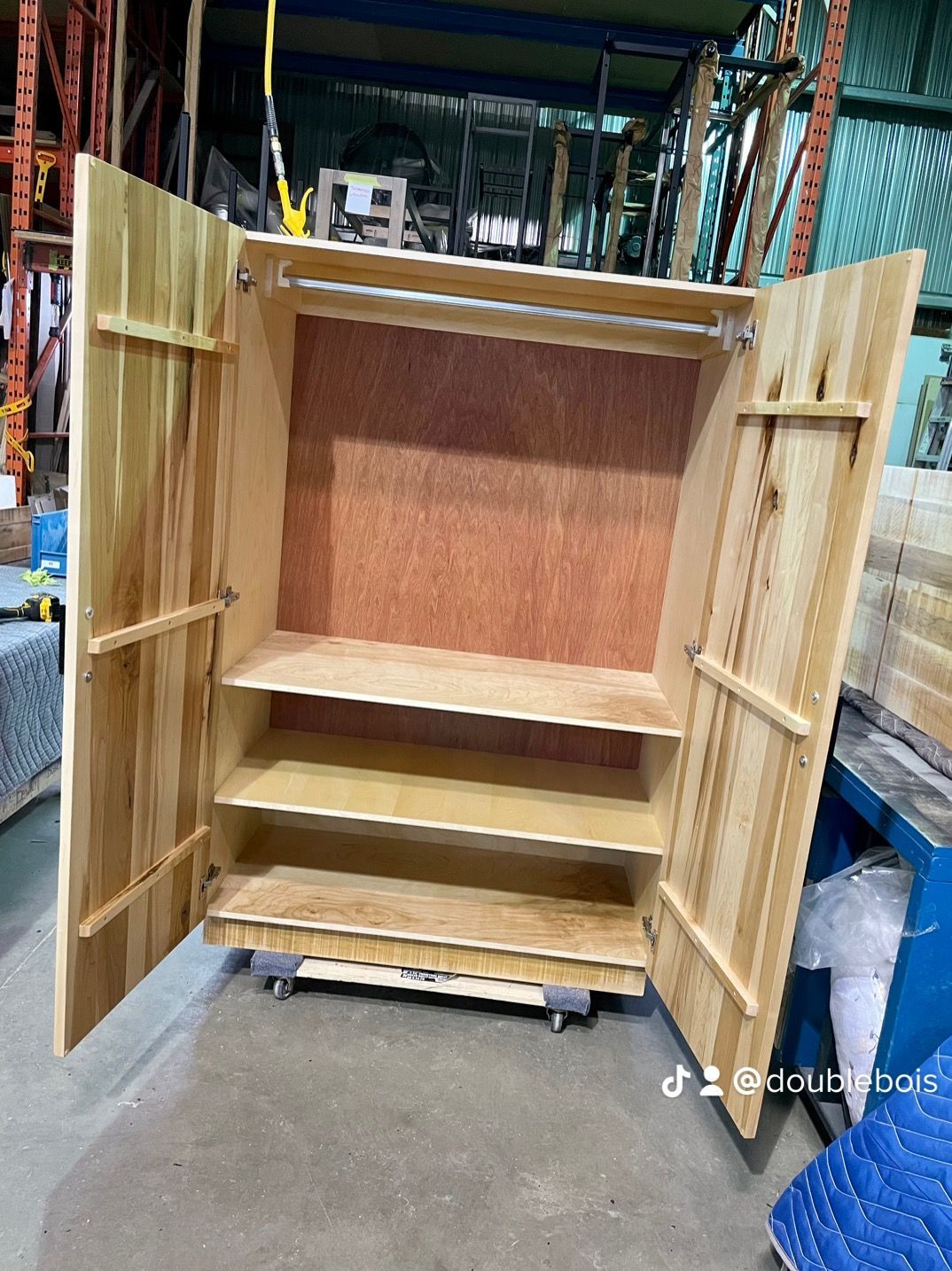 Une armoire en bois avec les portes ouvertes se trouve dans un entrepôt.