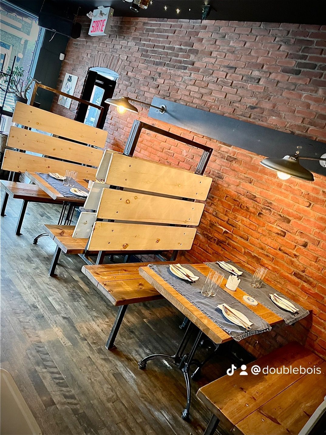 Un restaurant avec des tables et des bancs en bois et un mur de briques.
