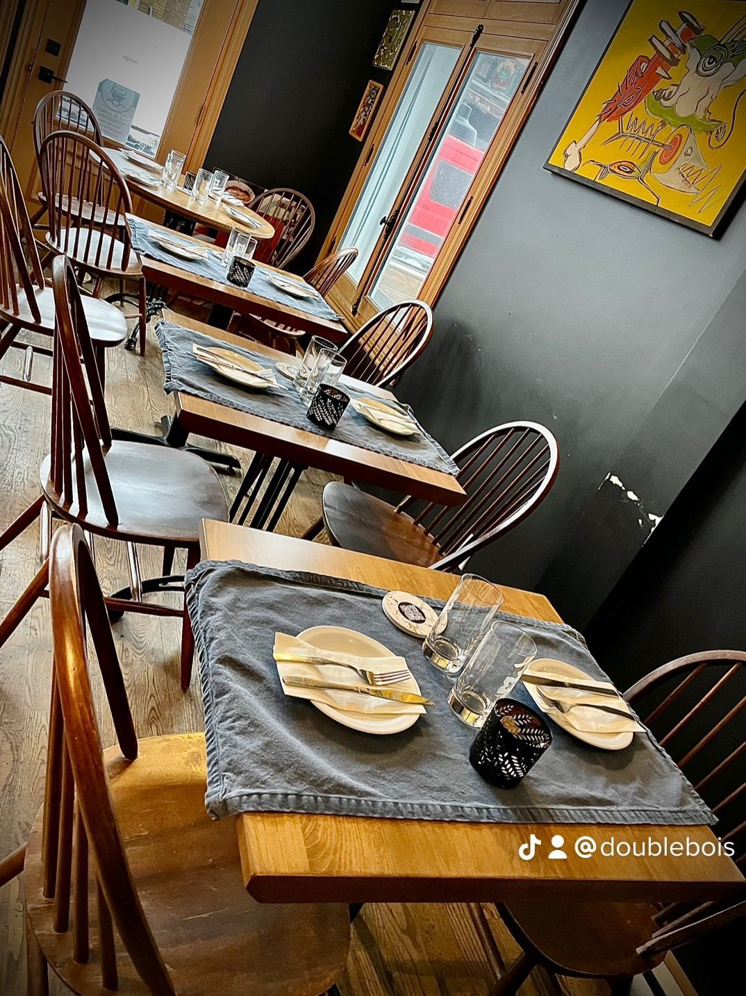 Un restaurant avec des tables, des chaises et des assiettes dessus.