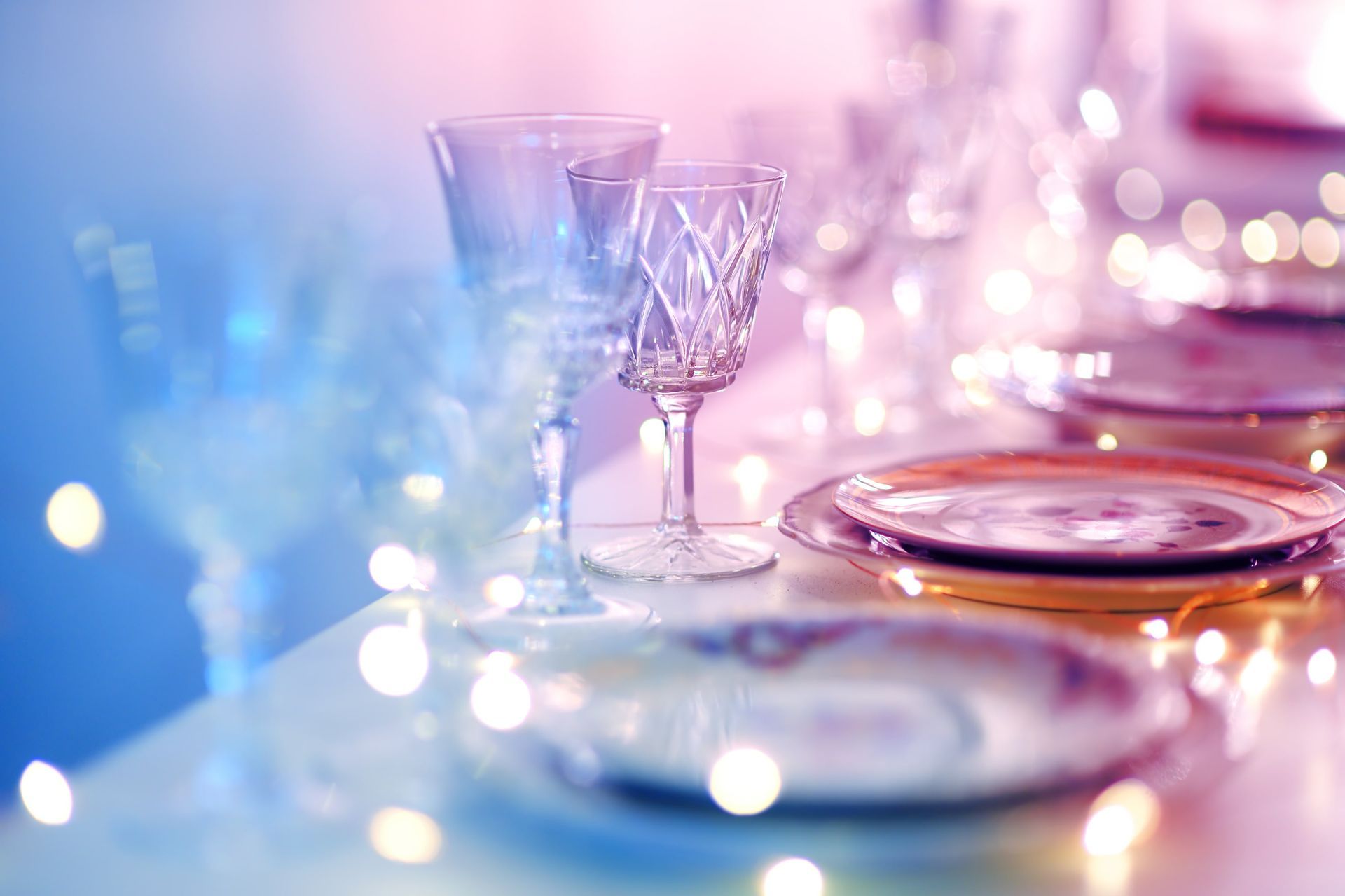 A table set for a dinner party with plates and wine glasses.