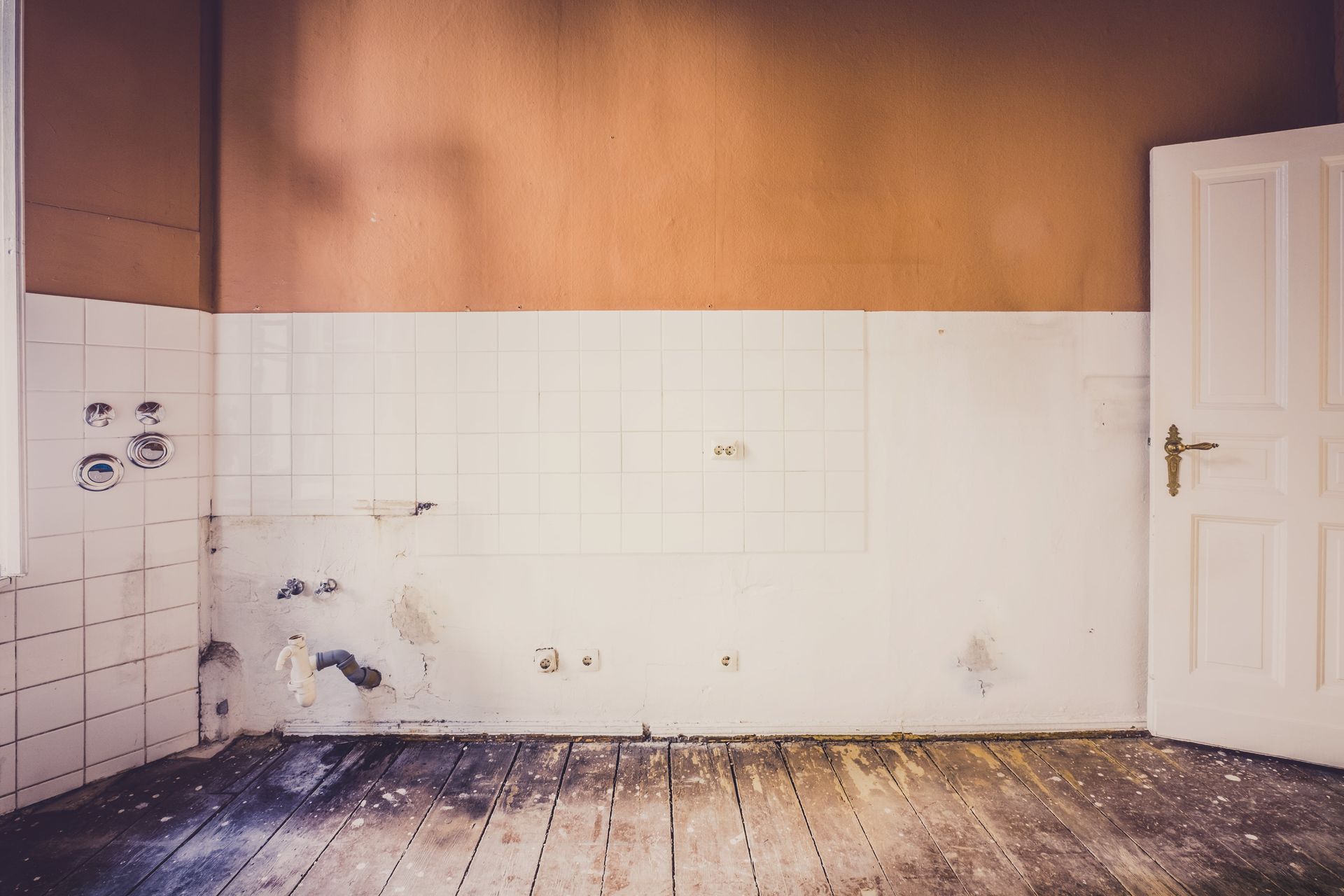 An empty room with a wooden floor and a white door.