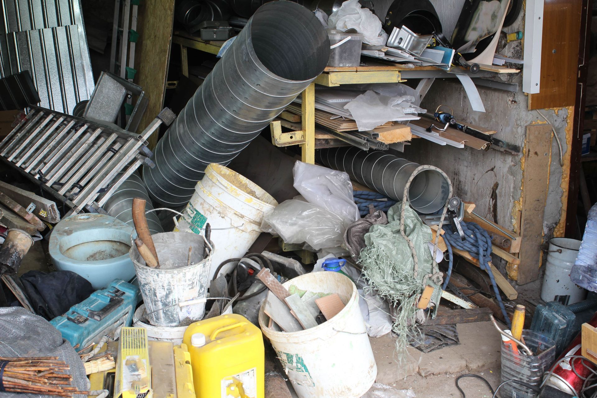 A pile of buckets , pipes , and other items in a garage.