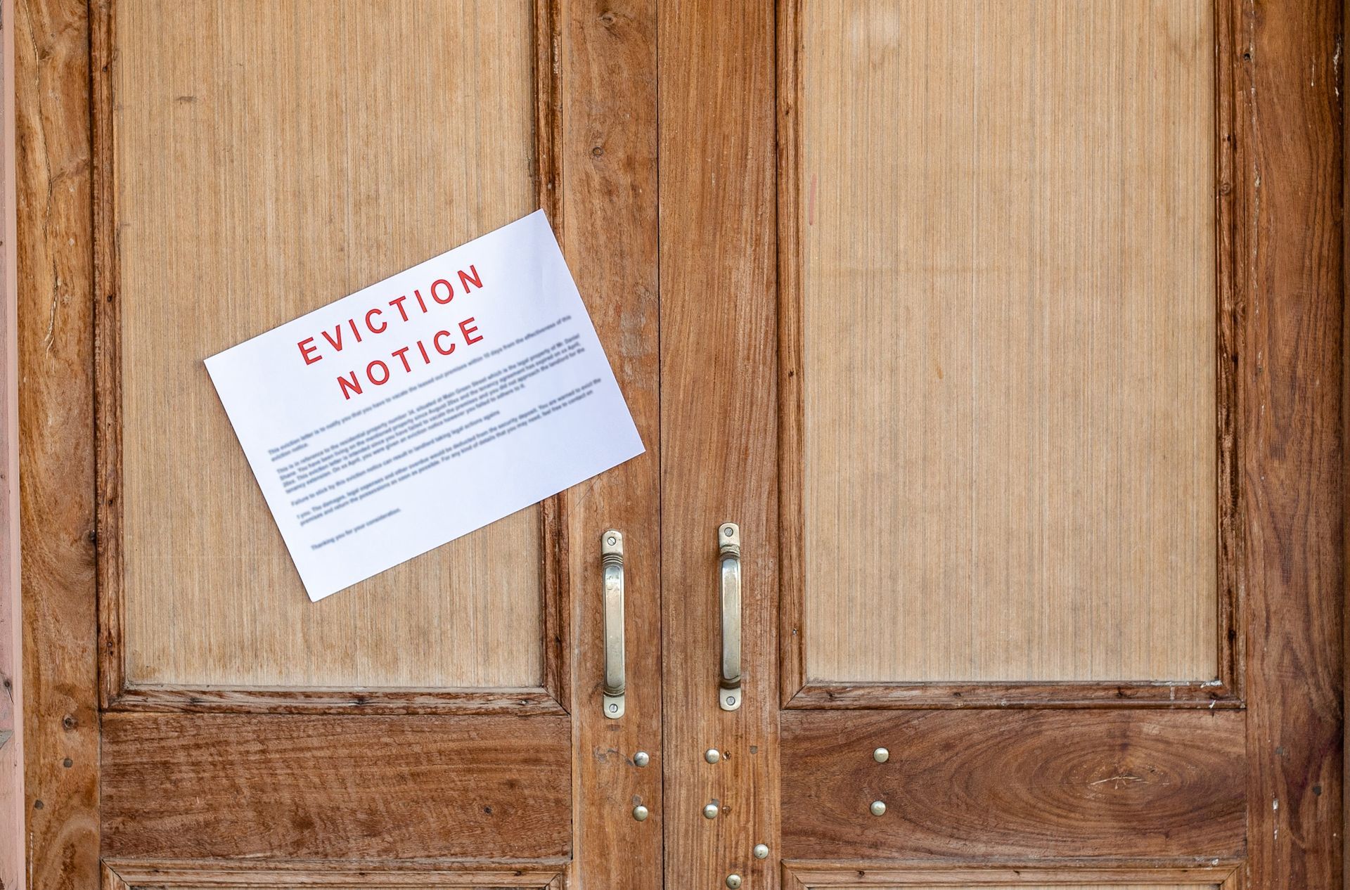 An eviction notice is hanging on a wooden door.