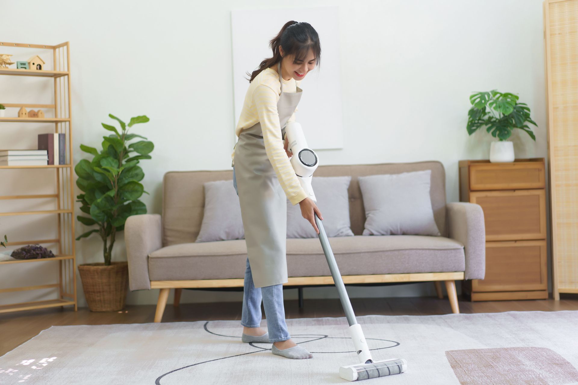A woman is cleaning the floor with a vacuum cleaner in a living room.