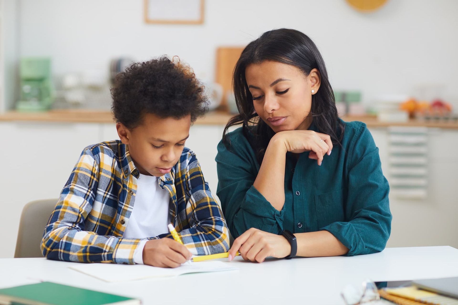 A woman helping a young boy with his homework.