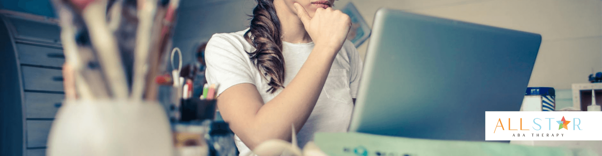 Female therapist wearing glasses concentrating while working on a laptop at a desk in Maryland.