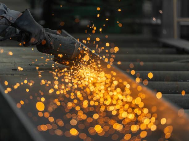 Technician cutting steel structure with metal stripping abrasives, sparks flying, precision work, industrial workshop