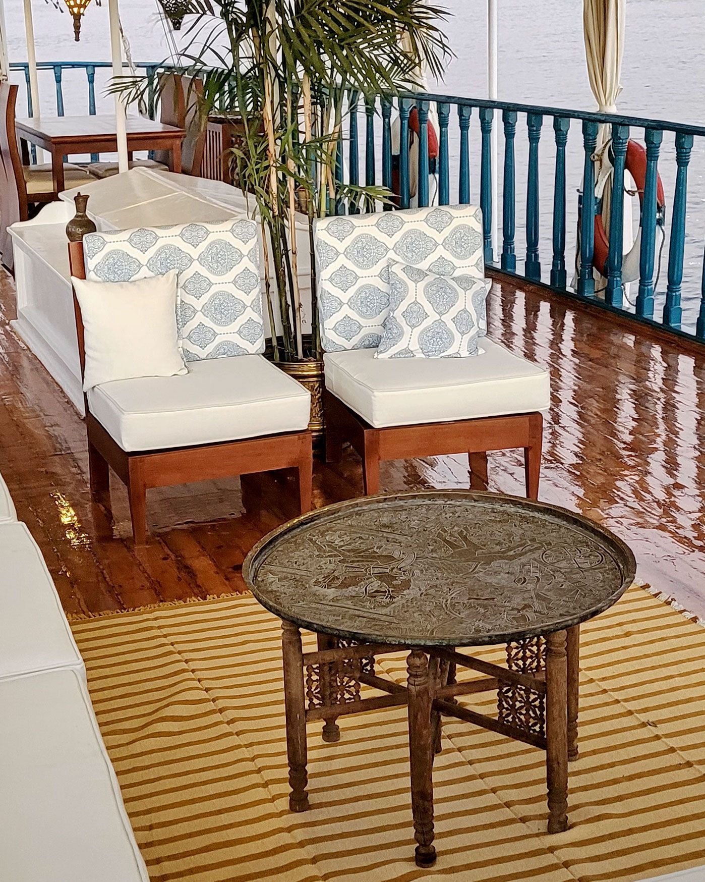 A photo of a cozy seating area on the deck of a traditional Egyptian sailing boat, the Dahabiya Kingfisher, which offers private cruises along the Nile river between Luxor and Aswan.