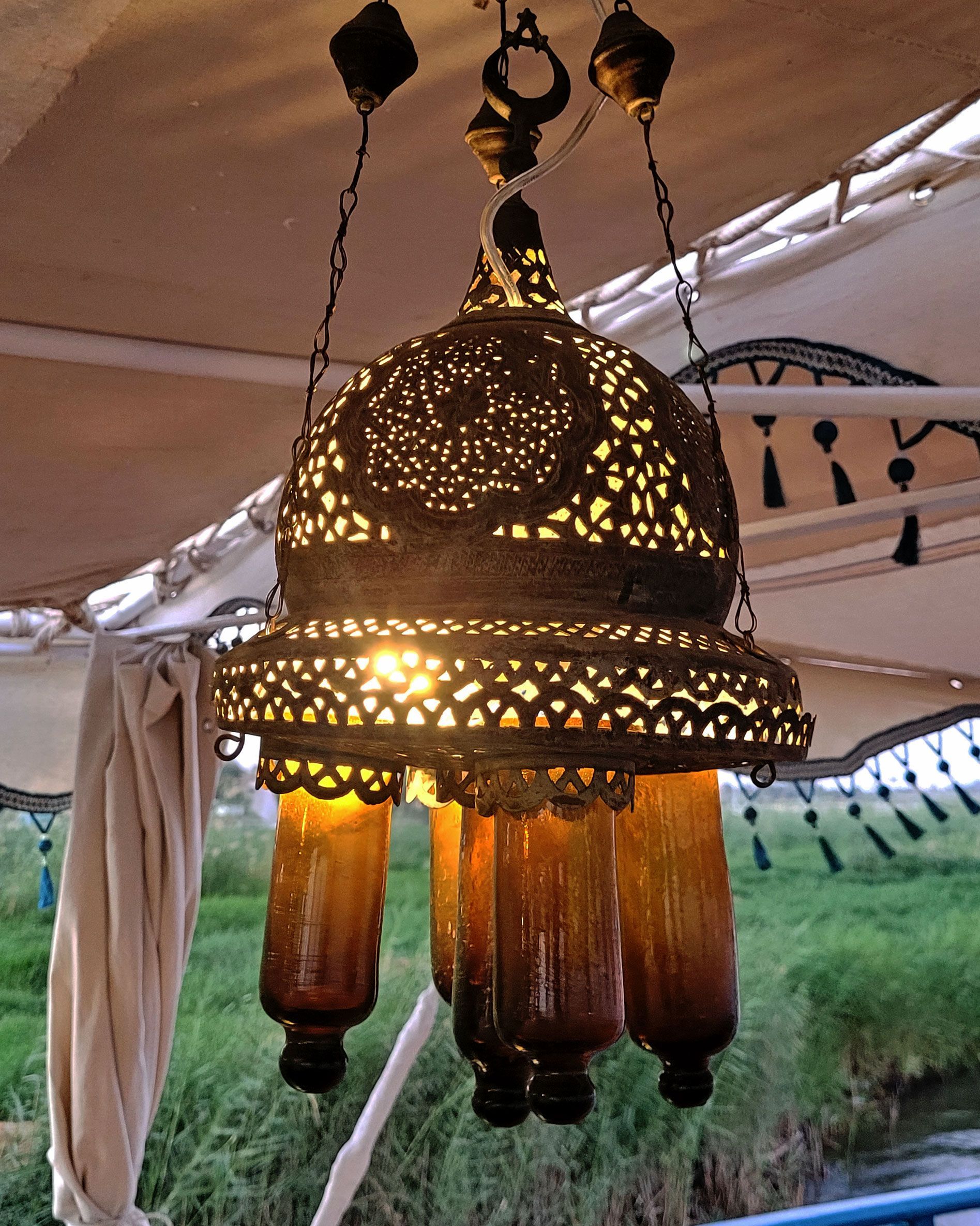 An antique copper lamp on a historic boat sailing the Nile. The boat is the Dahabiya Kingfisher, which was built in 1899 and offers private cruises between Luxor and Aswan in Egypt.