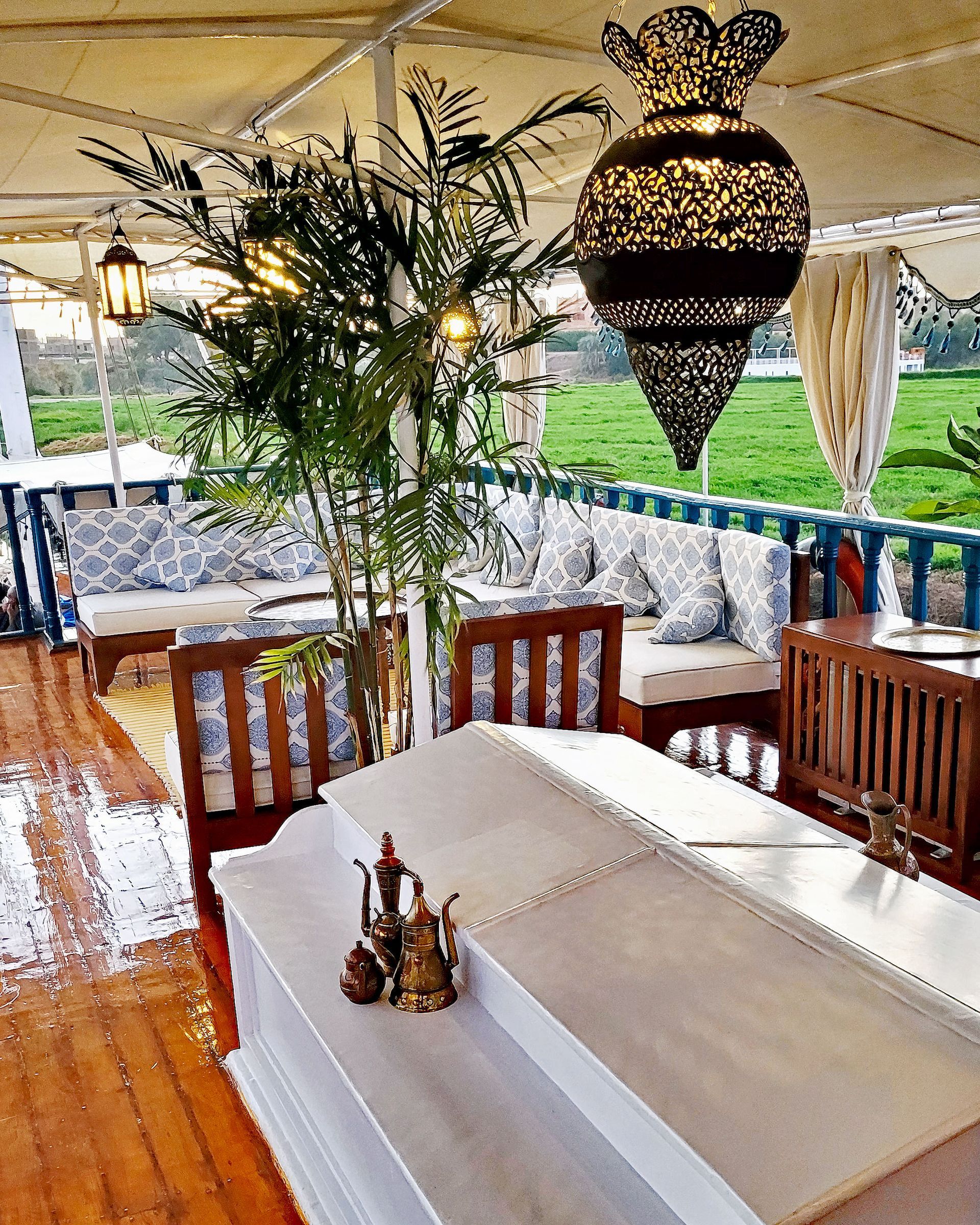 A photo of a cozy seating area on the deck of a traditional Egyptian sailing boat, the Dahabiya Kingfisher, which offers private cruises along the Nile river between Luxor and Aswan.